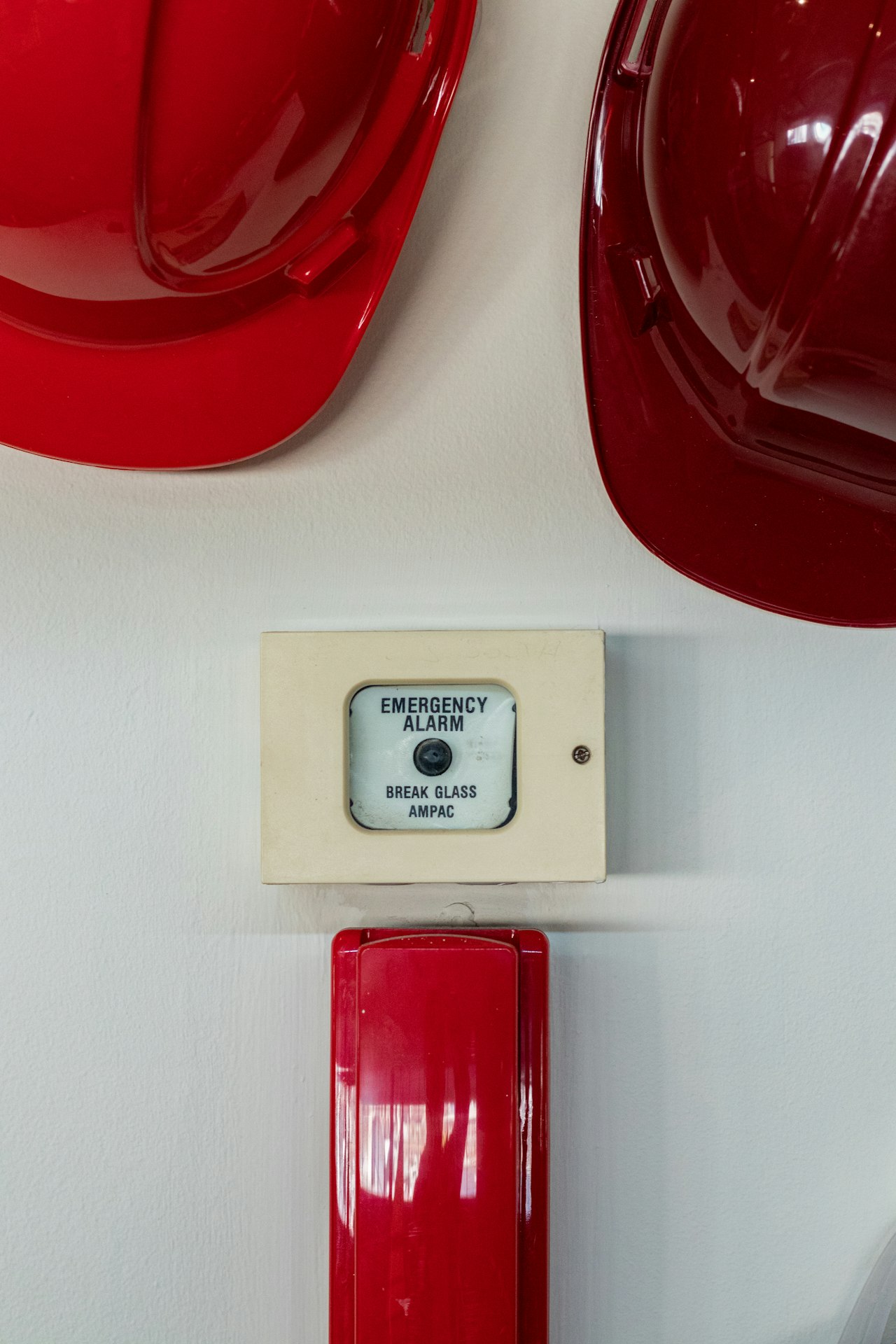 Bouton d'alarme incendie d'urgence et casques de sécurité rouges fixés sur un mur