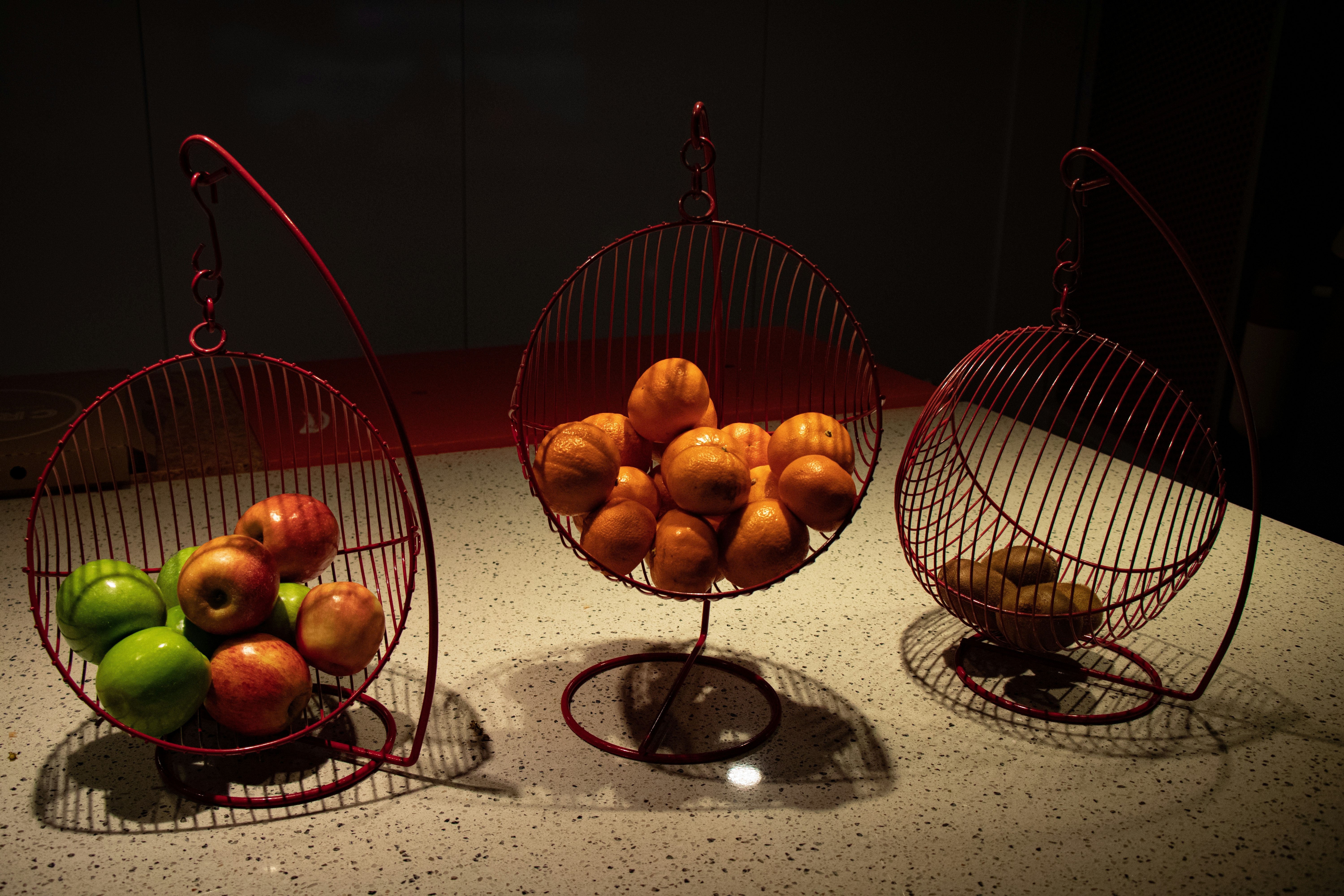 three baskets of fruits beside wall
