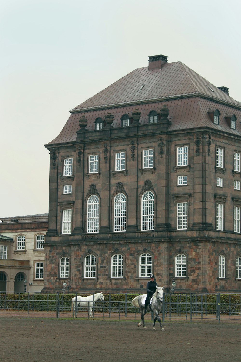 man riding horse near gray concrete building