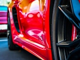 A close-up view of a red sports car prominently displaying the GTS badge on its side. Part of the wheel is visible, emphasizing the sleek design and detailing typical of high-performance vehicles.