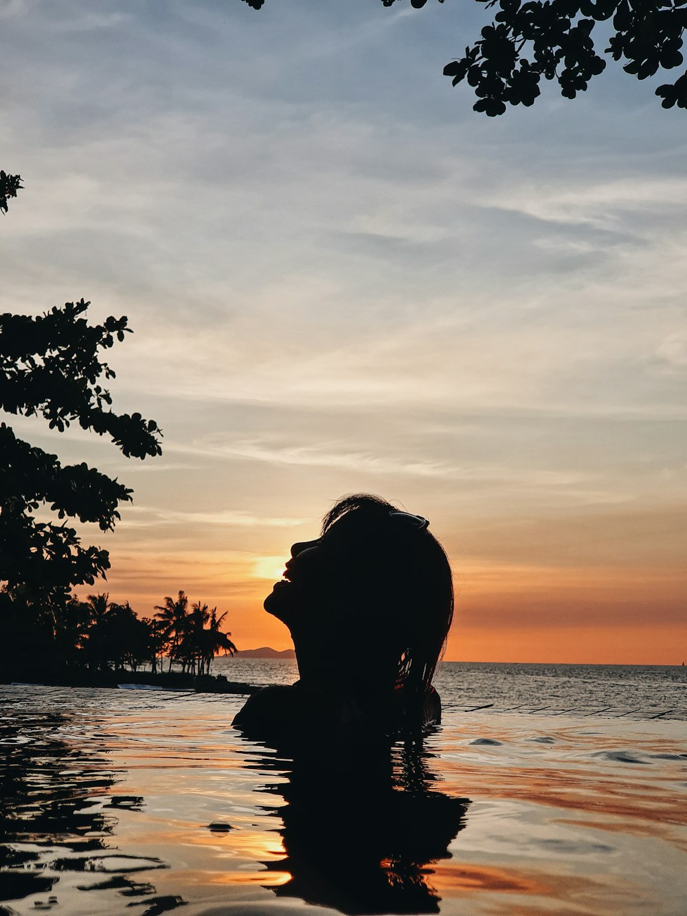 silhouette of woman in body of water during golden hour