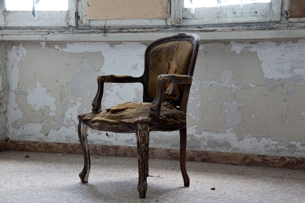 brown padded wooden armchair near wall