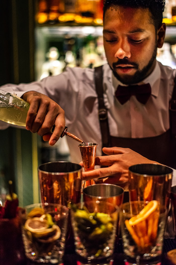 Bartender measuring a pour into a copper jigger