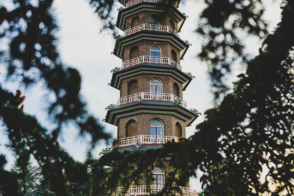 low-angle photography of brown tower building surrounded with green trees