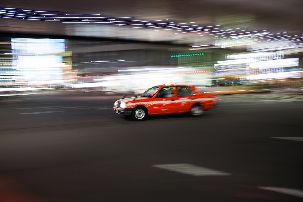 time lapse photography of a passing red sedan