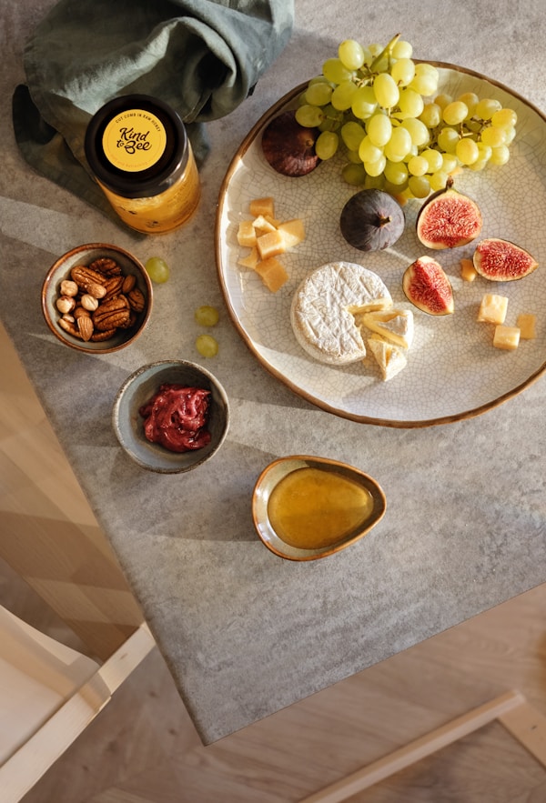 Green grapes near, sliced fig, and mangosteen fruit on plate near walnut and olive oil