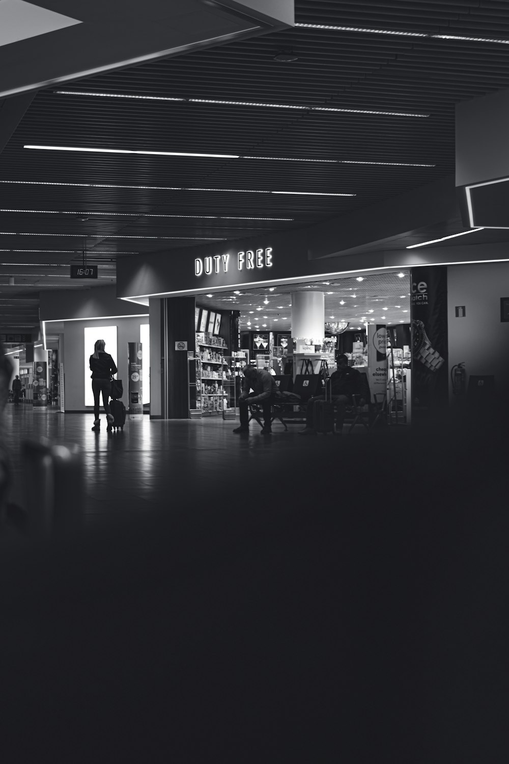 a black and white photo of people walking through an airport