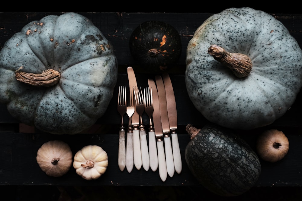 grey stainless steel forks and knives between two green pumpkins