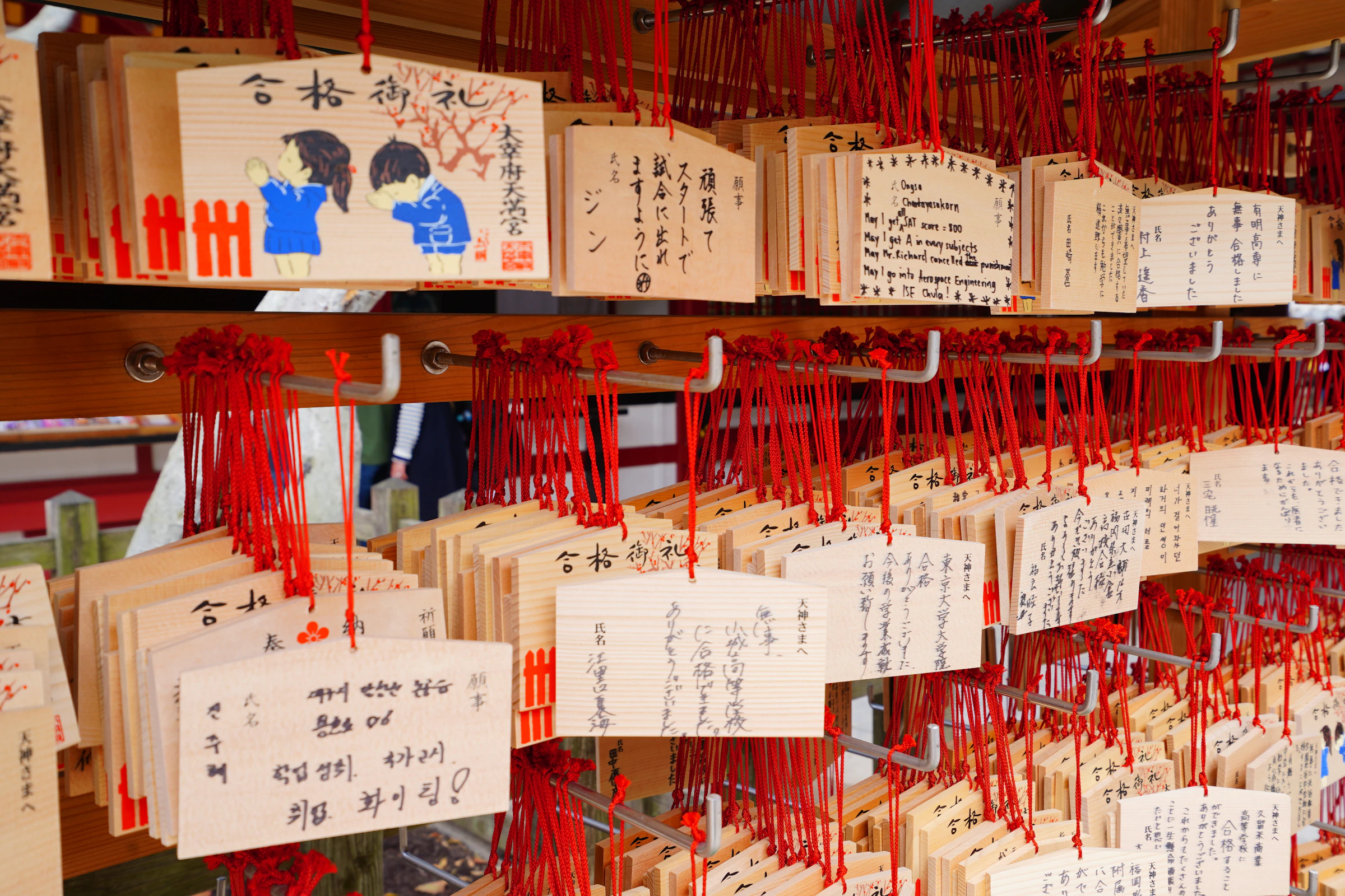 Wooden ema wishing plaques hung at Dazaifu Tenmangu shrine, many written with hopes for exam success