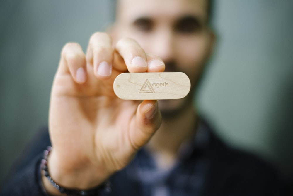 selective focus photography of man in holding wooden ornament