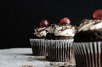 three chocolate cupcakes with cherries