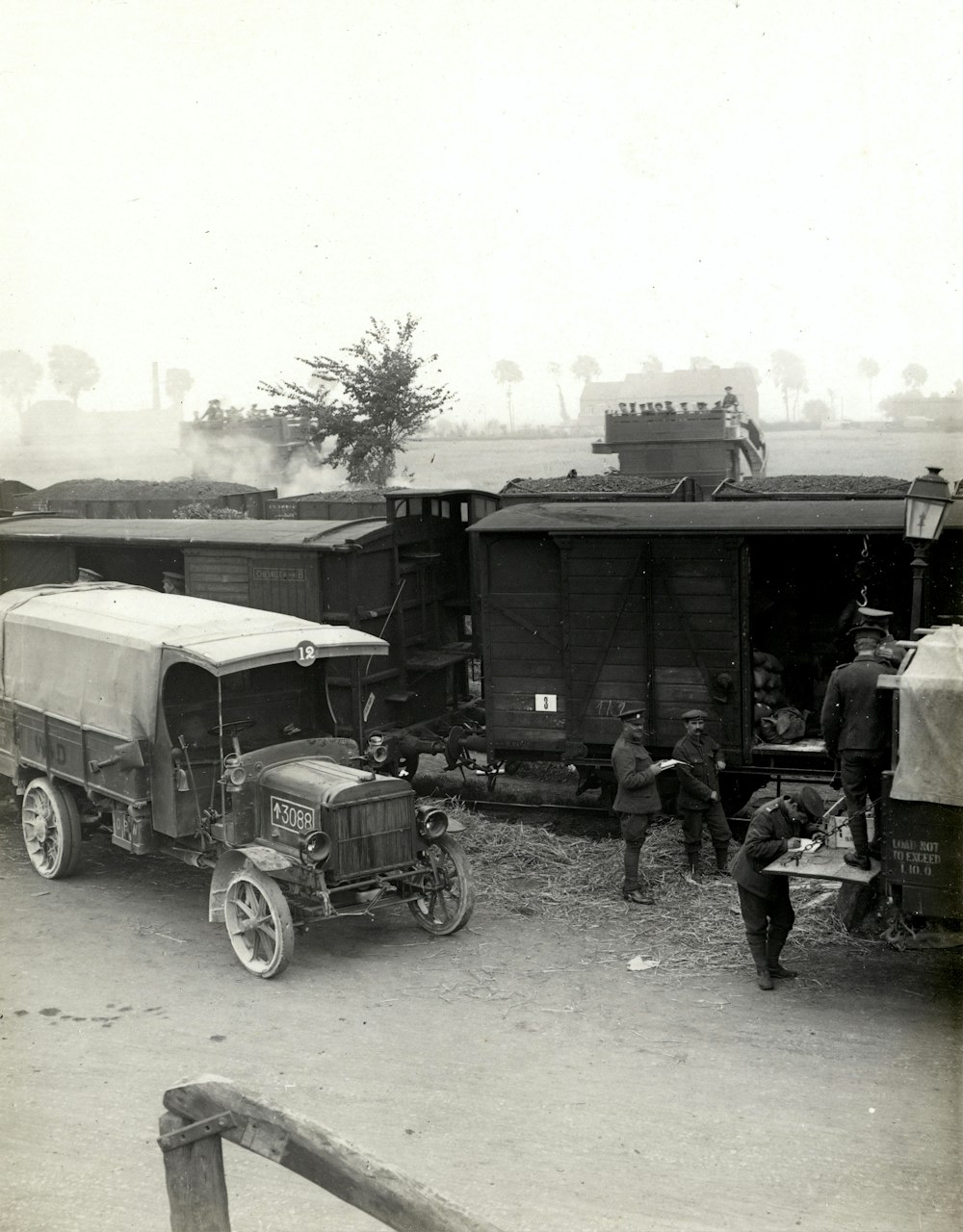greyscale photo of vehicles beside train