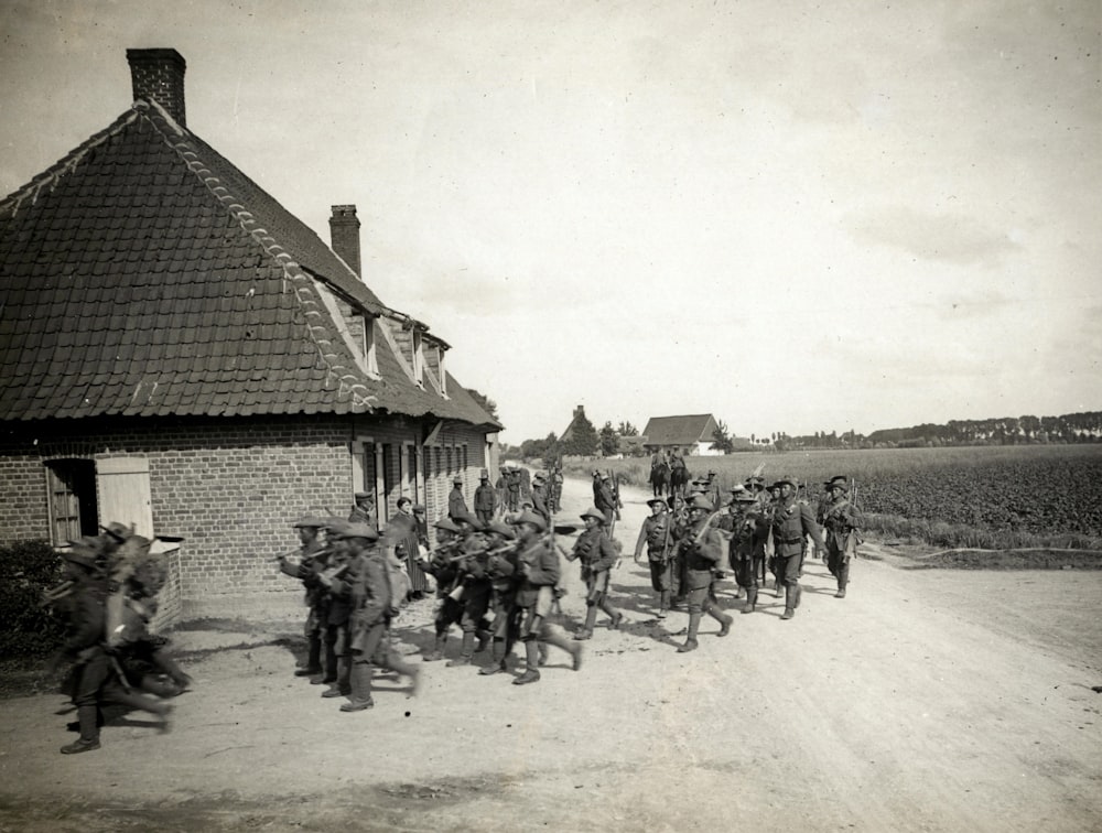 grayscale photo of men standing beside houses