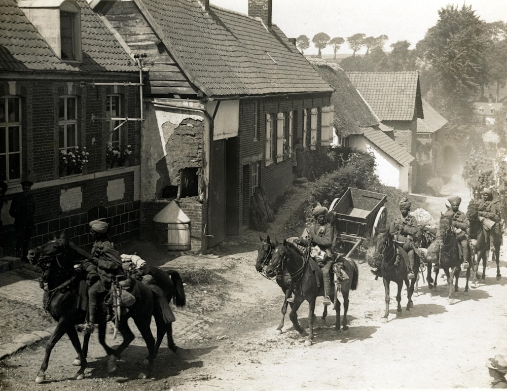 Menschen, die neben Häusern reiten, Graustufenfotografie