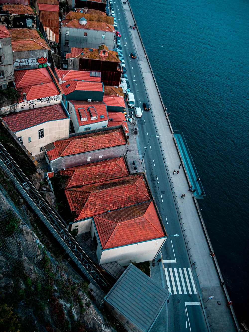 vehicles and people on roadway beside sea