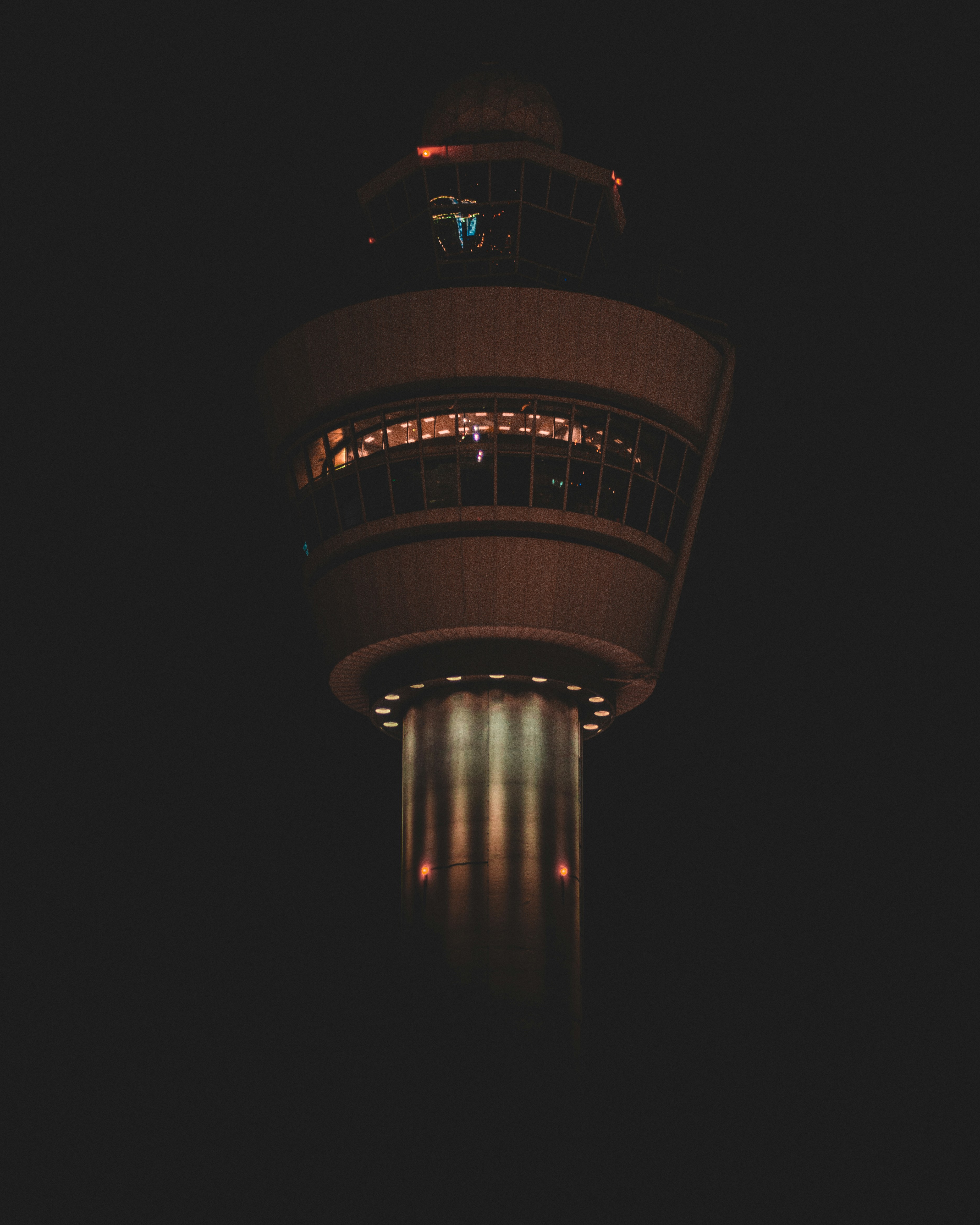 Air traffic control tower illuminated against the night sky.
