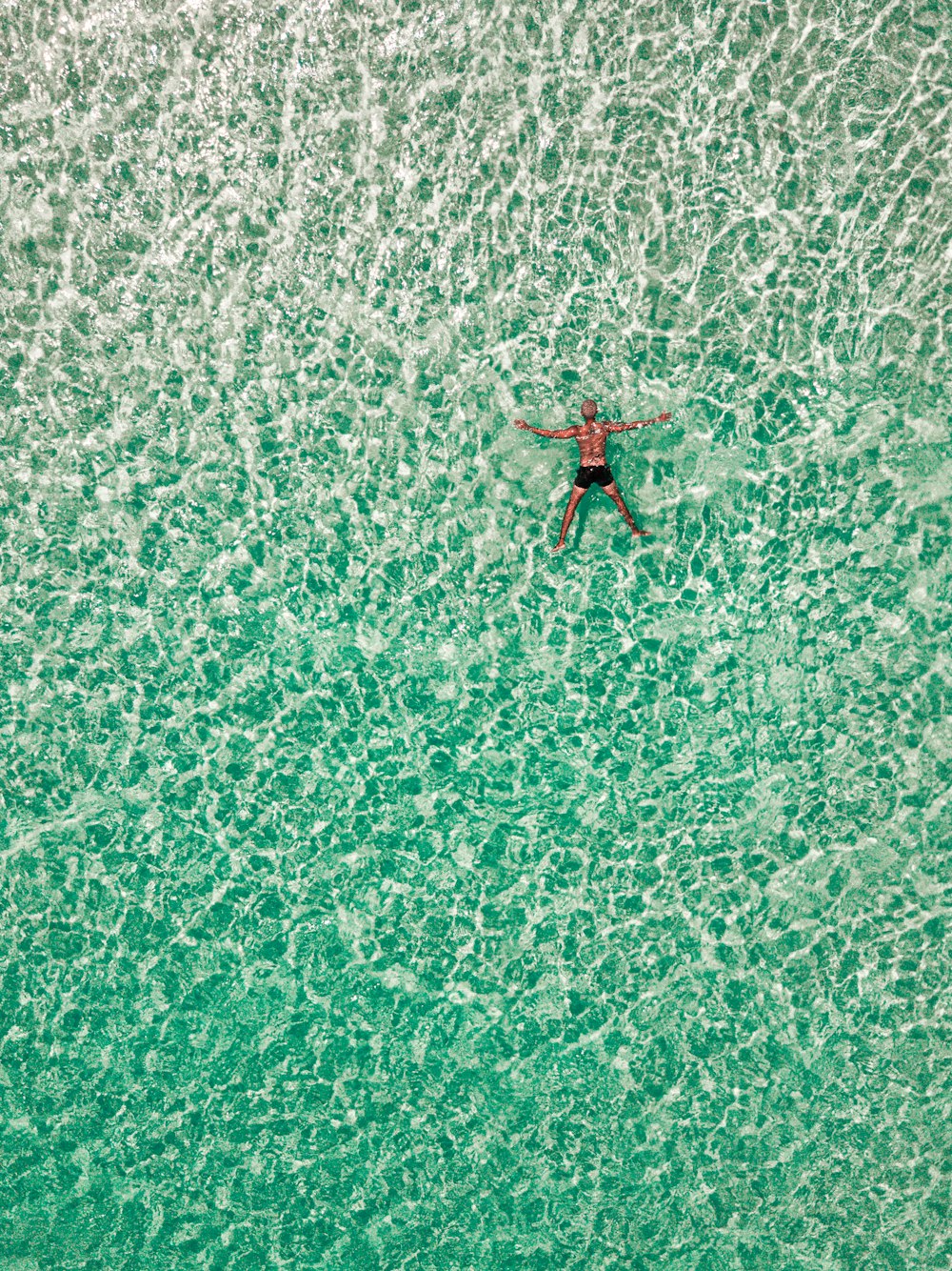 a man is swimming in the ocean on a surfboard