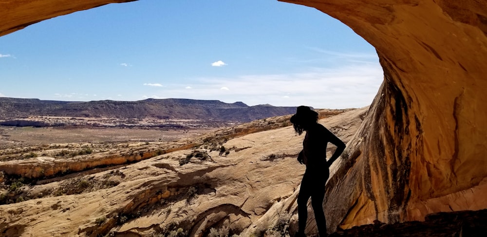 silhouette of woman under rock formation