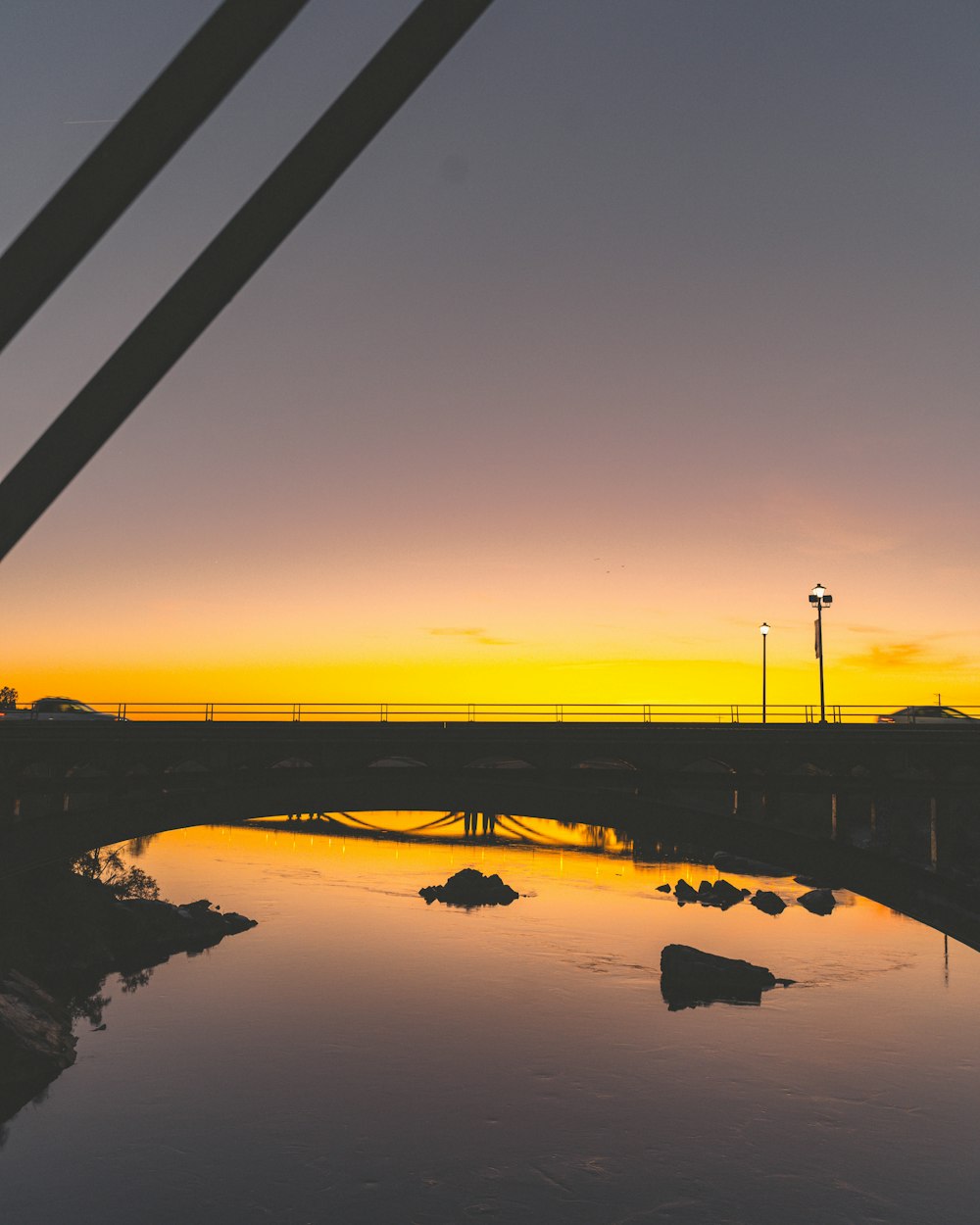 silhouette of bridge over river at sunset