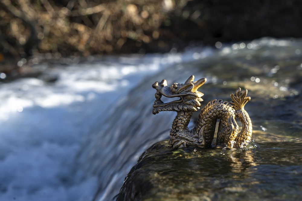 gold-colored dragon figurine on cliff with flowing water