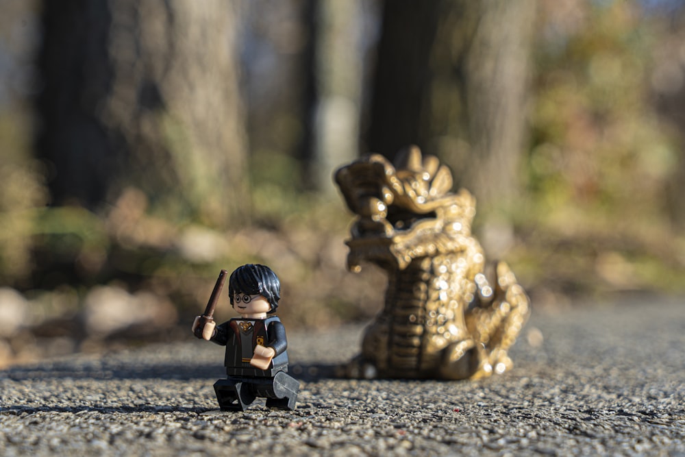 fotografía de enfoque selectivo de la minifig de Harry Potter por la figura del dragón en el pavimento