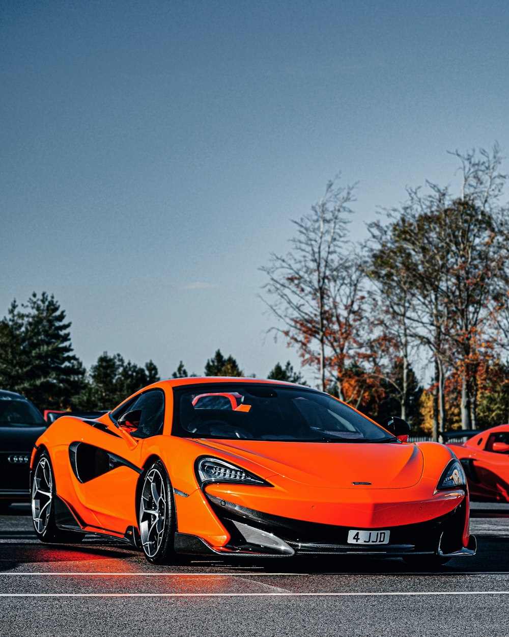 parked orange car near cars and trees