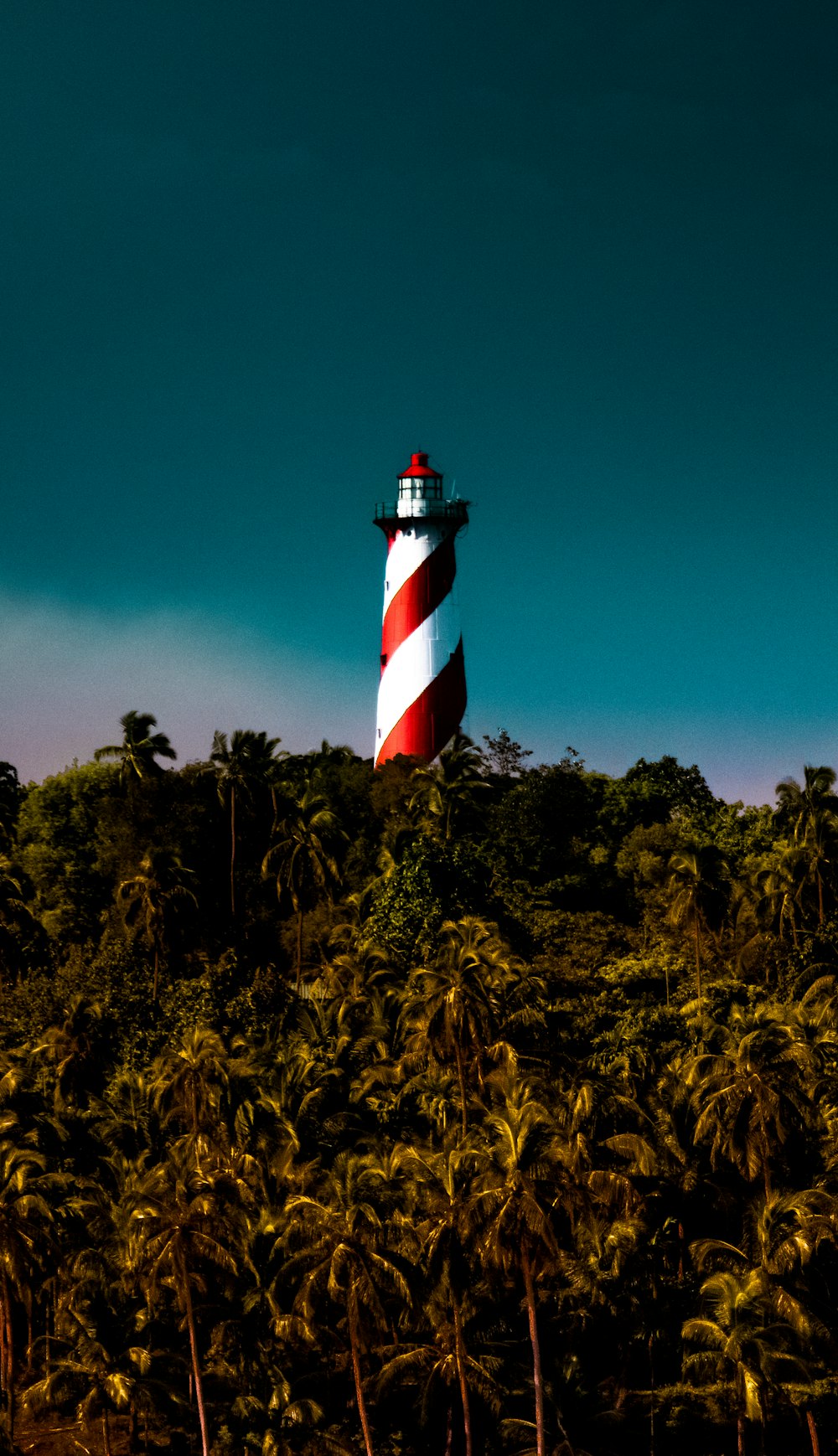 white and red striped lighthouse under a blue sky