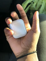 A hand holding a trendy AirPods cover against a bright, youthful backdrop.