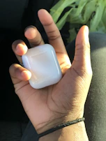 Dynamic photo of a hand holding a glowing gadzhub AirPods case with smooth glassmorphism effects in the background.