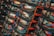 A large stack of crab pots or traps, each containing ropes, buoys, and other fishing equipment. The traps are primarily black with some orange, and have identification tags attached. The scene looks busy and complex due to the overlapping structure of the traps.