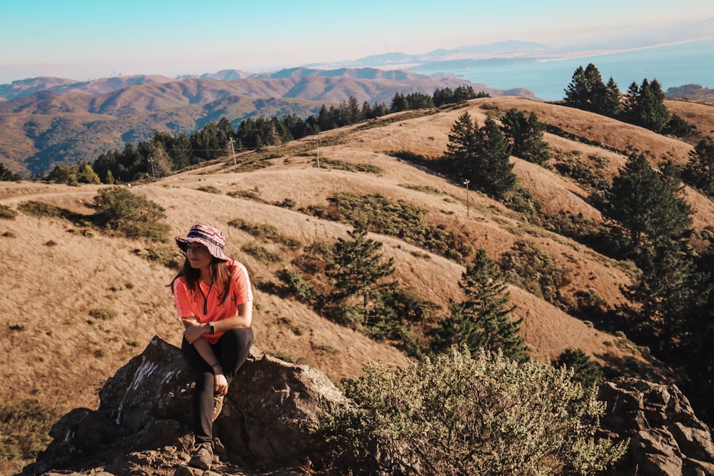 woman sitting on rock near mountain range