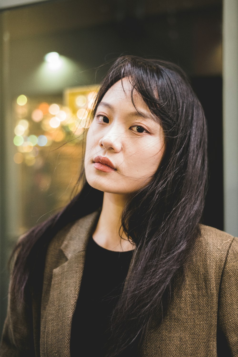 a woman with long black hair standing in front of a building