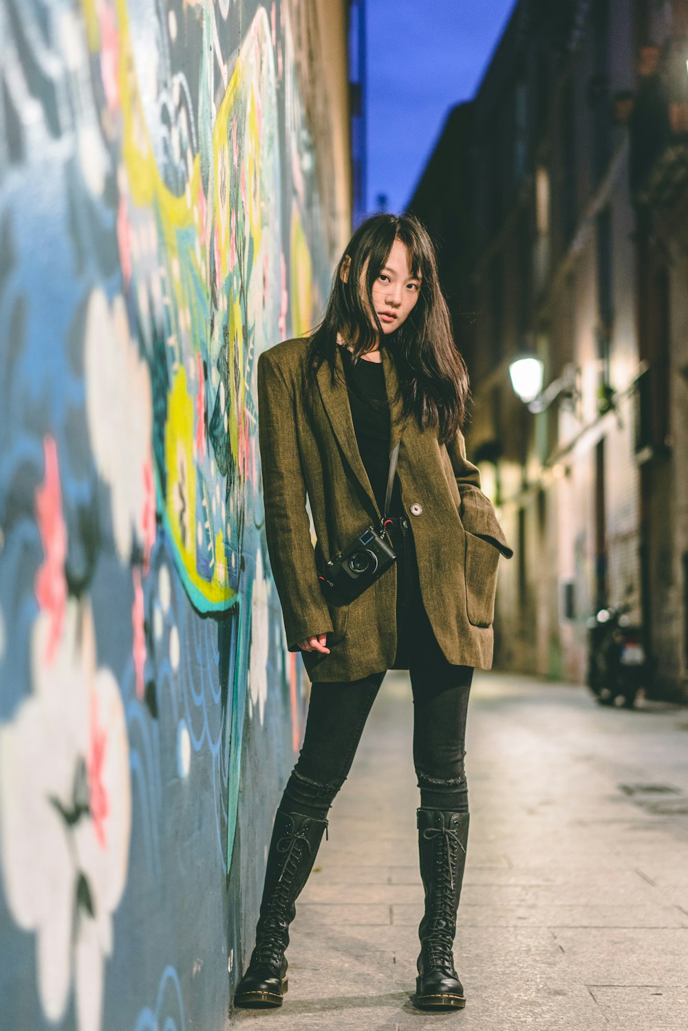 woman wearing green jacket standing near the wall