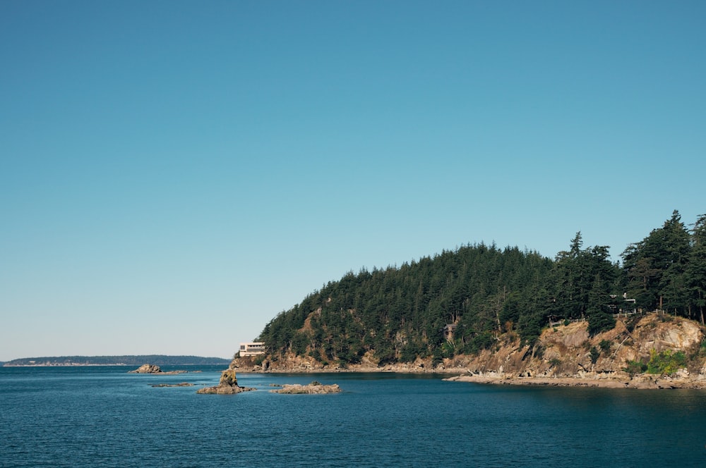 house near cliff and body of water viewing mountain