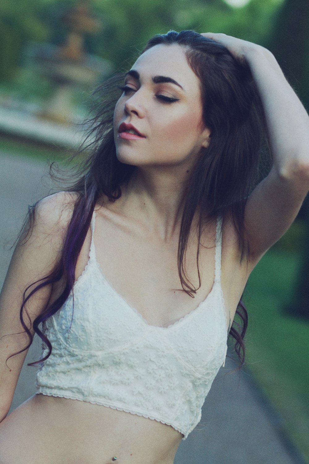 woman wearing white spaghetti strap top standing while touching her hair