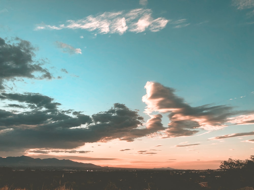 the sun is setting over the mountains with clouds in the sky