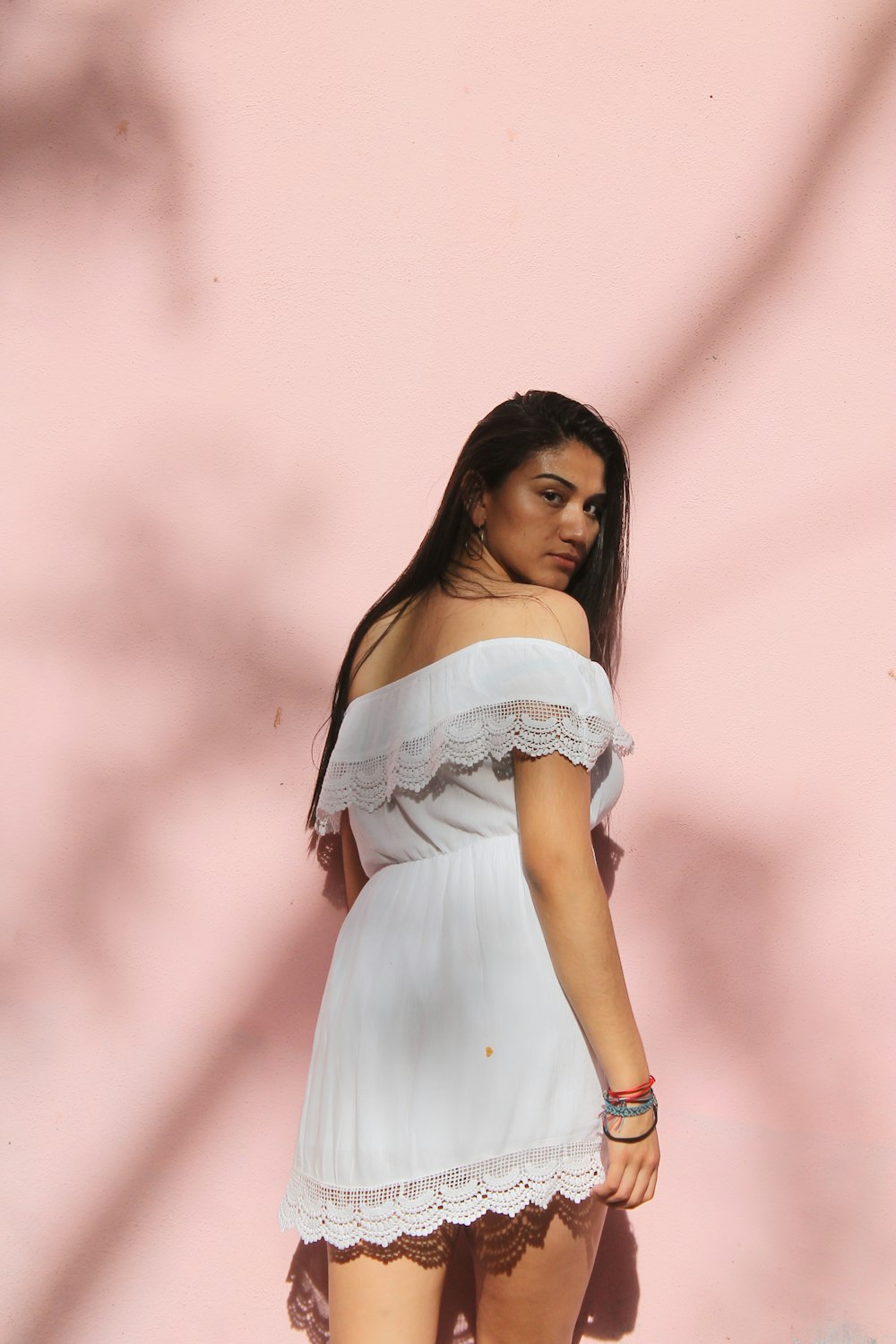 woman wearing white lace off-shoulder mini dress standing while glancing her right side