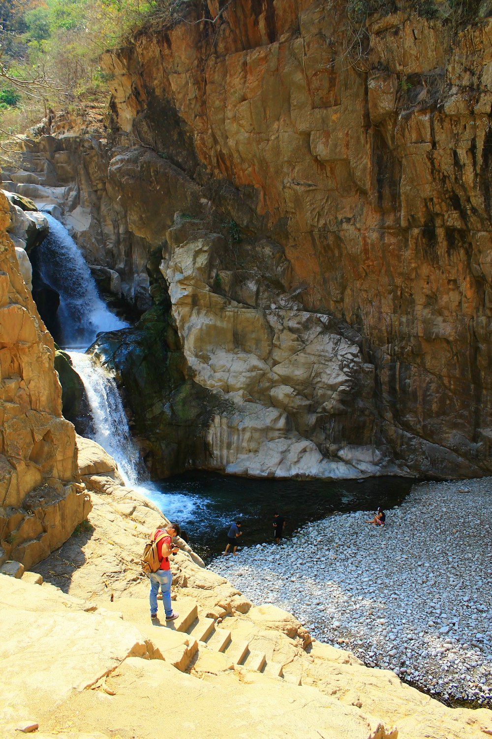 person standing on rocky mountain near waterfalls