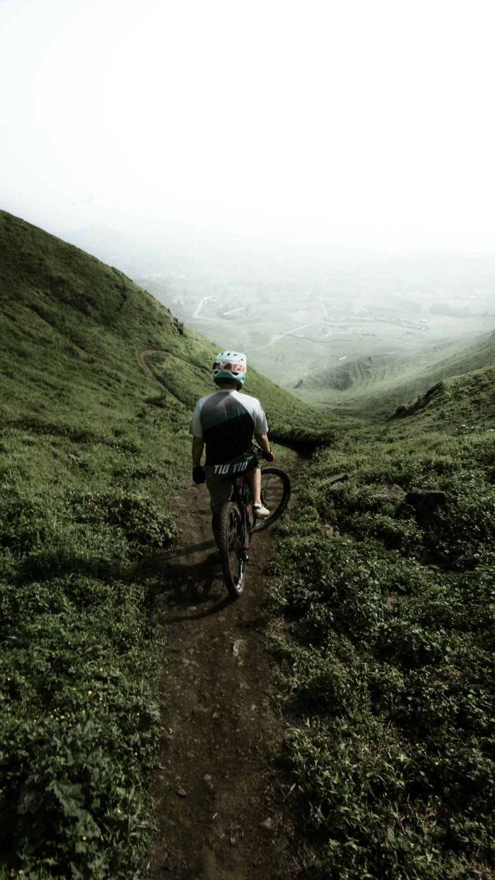 白い空の下、丘の上を自転車で走る男