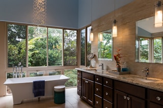 white freestanding bathtub and brown wooden cabinets