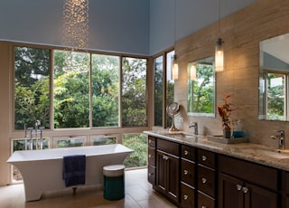 white freestanding bathtub and brown wooden cabinets