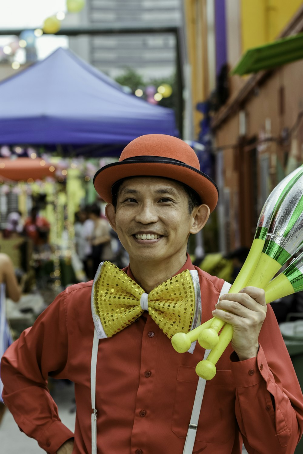 man in red and black fedora hat holding yellow toys