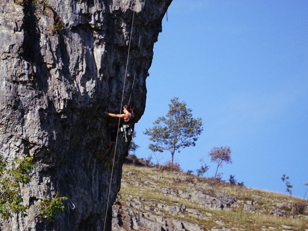 person rock climbing under blue sky
