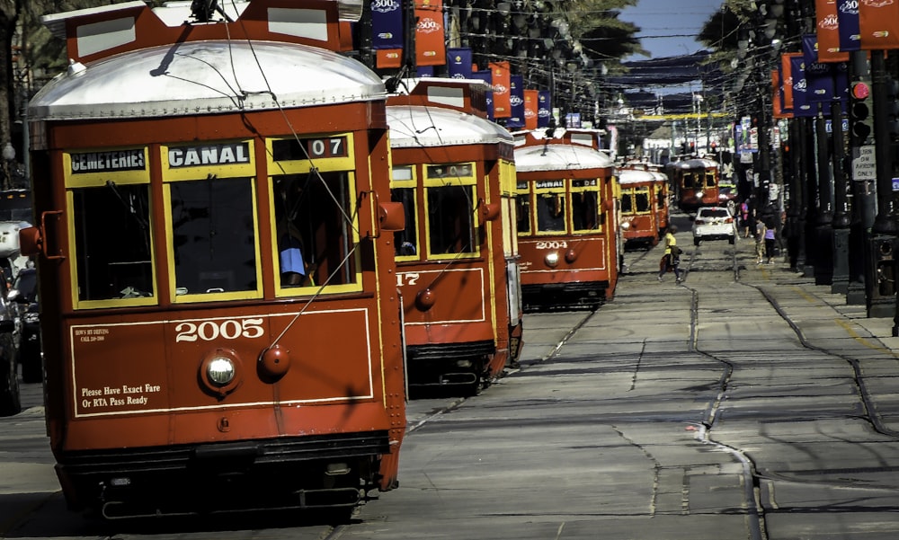 a row of red trolley cars traveling down a street
