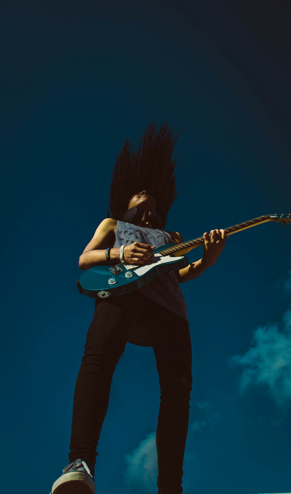 low-angle photography of man playing guitar during daytime