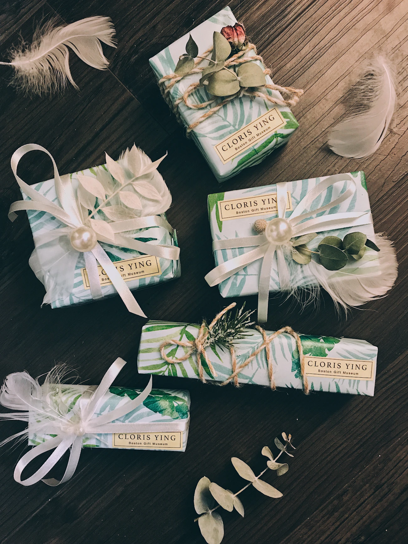 Five carefully wrapped gift boxes arranged with ribbons and greenery