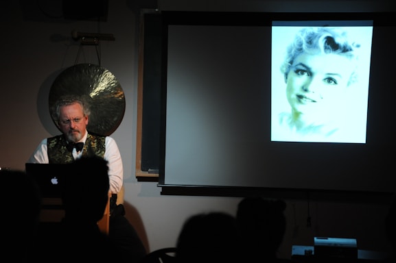 Girish Narkhede speaking at a political event, with a laptop and digital marketing materials visible.