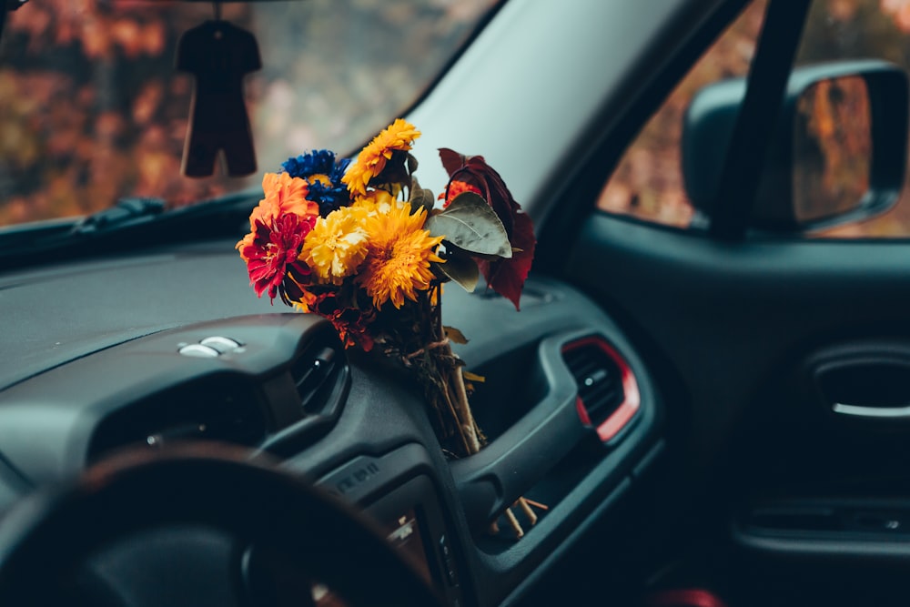 selective focus photography of brown petaled flowers on vehicle's dashboard