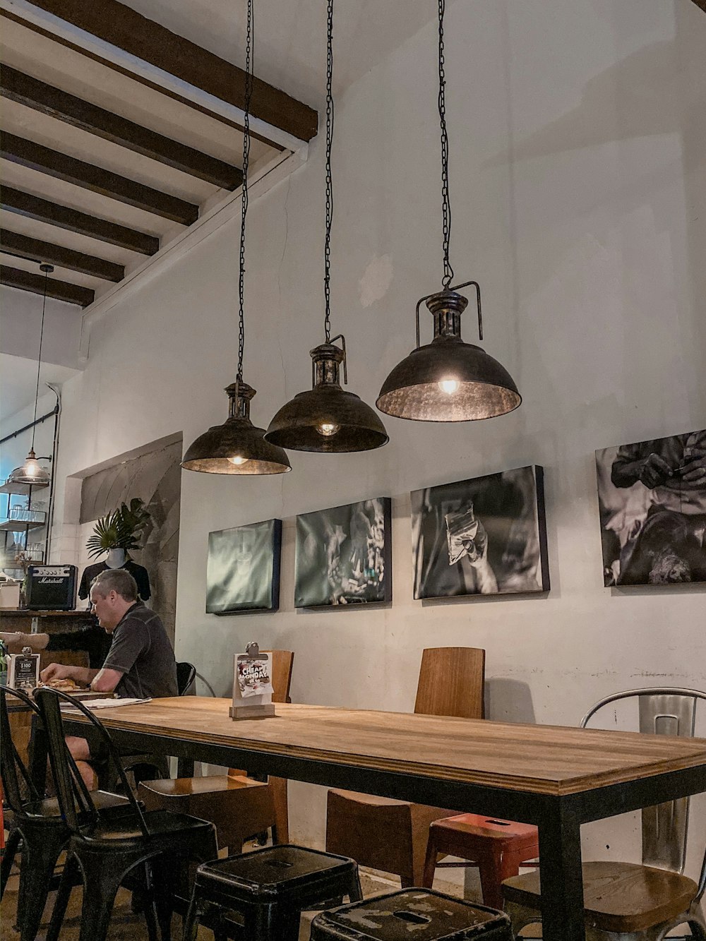 man sitting at table under three pendant lamps