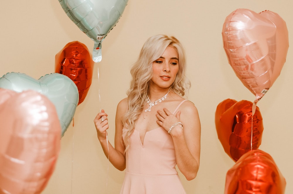 woman wearing pink spaghetti strap dress standing near the balloon